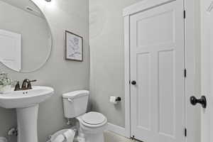 Bathroom with toilet, a sink, and baseboards