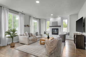 Living area featuring recessed lighting, hardwood / wood-style flooring, a high end fireplace, baseboards, and plenty of natural light