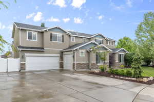 View of front of property featuring stone siding, stucco siding, an attached garage, fence, and driveway