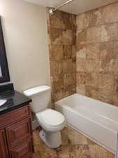 Bathroom featuring toilet, vanity, a textured ceiling, and washtub / shower combination