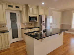 Kitchen with cream cabinetry, stainless steel appliances, a sink, ornamental molding, and a textured ceiling