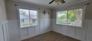 Unfurnished dining area featuring a decorative wall, a wainscoted wall, carpet flooring, and a ceiling fan