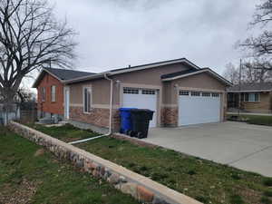 View of front of house with a garage, driveway, stone siding, and stucco siding