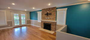Unfurnished living room with ornamental molding, french doors, wood finished floors, recessed lighting, and baseboards