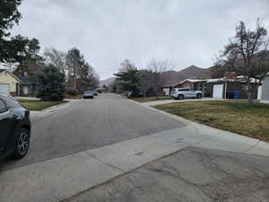 View of asphalt road featuring a residential view and curbs