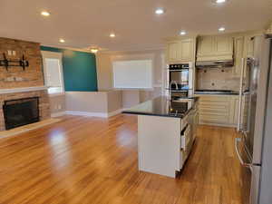 Kitchen with appliances with stainless steel finishes, a sink, dark countertops, light wood-type flooring, and baseboards