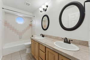 Full bathroom featuring tile patterned flooring, shower / bath combination, toilet, and double vanity