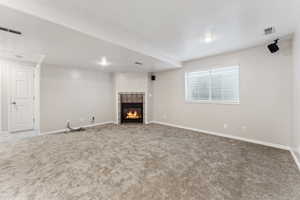 Unfurnished living room featuring carpet, a tiled fireplace, baseboards, and recessed lighting