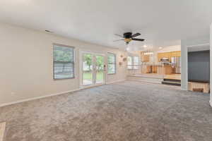 Unfurnished living room with a ceiling fan, carpet floors, and baseboards