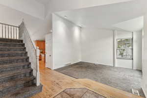 Staircase with baseboards, vaulted ceiling, wood finished floors, and carpet floors
