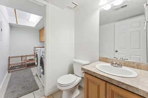 Bathroom featuring washing machine and dryer, toilet, vanity, tile patterned floors, and baseboards