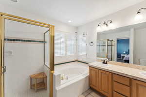 Ensuite bathroom featuring a jetted tub, tile patterned floors, a stall shower, and double vanity