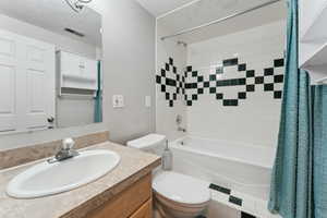 Bathroom with toilet, shower / bath combination with curtain, and vanity