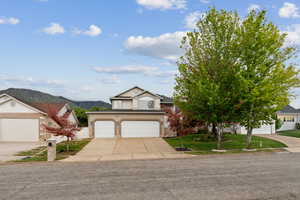 View of front facade with concrete driveway, a front lawn, a mountain view, brick siding, and a garage
