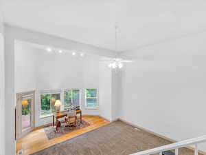 Office area featuring a high ceiling, wood finished floors, ceiling fan, baseboards, and carpet