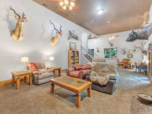 Living area with ceiling fan, carpet, stairway, and baseboards