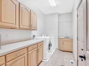 Clothes washing area featuring cabinet space and washing machine and dryer