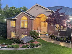View of front of home with brick siding, a front yard, and a shingled roof