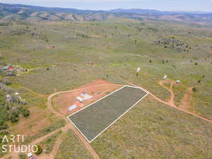 Aerial view of sparsely populated area with property parcel outlined and a mountainous background