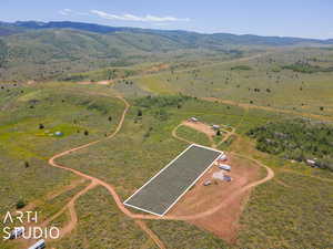 Aerial view of property and surrounding area featuring property parcel outlined, a mountainous background, and rural landscape