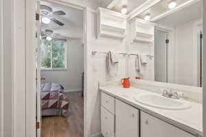 Bathroom with wood finished floors, vanity, baseboards, a ceiling fan, and a textured ceiling
