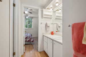 Bathroom featuring wood finished floors, vanity, a ceiling fan, and baseboards
