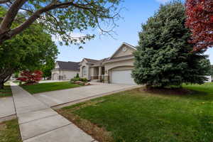 View of front of house featuring stucco siding, concrete driveway, a front yard, and an attached garage