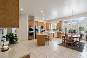 Kitchen featuring appliances with stainless steel finishes, a breakfast bar area, light countertops, a center island, and a chandelier