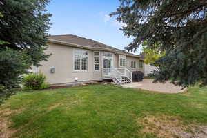 Rear view of house featuring stucco siding, a lawn, and a patio