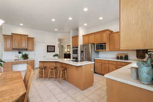 Kitchen featuring appliances with stainless steel finishes, arched walkways, a kitchen island, a kitchen bar, and recessed lighting