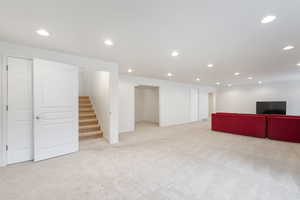 Finished basement living featuring carpet, stairway, angled from potential entry door window and facing potential kitchen location