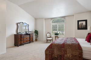 Carpeted bedroom with vaulted ceiling and baseboards