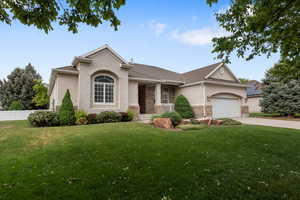 View of front facade with stucco siding, driveway, a garage, and covered porch