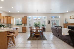 Dining area with a chandelier, light tile patterned floors, recessed lighting, and a tile fireplace