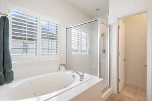 Bathroom with a jetted tub, a stall shower, and tile patterned floors