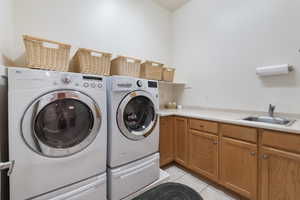 Washroom featuring separate washer and dryer, light tile patterned flooring, and cabinet space