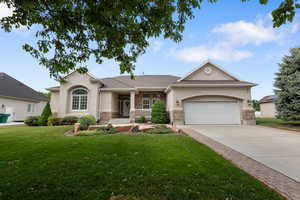 View of front of home with stucco siding, a front yard, driveway, and a garage