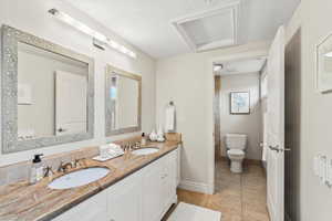Bathroom with tile patterned flooring, double vanity, toilet, and baseboards