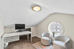 Carpeted office space featuring lofted ceiling and baseboards