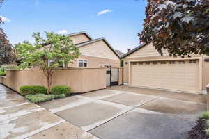 View of home's exterior featuring stucco siding, fence, a garage, and a gate