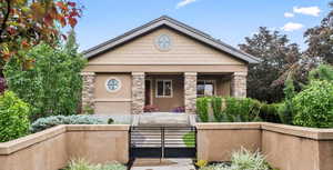 View of front of property featuring stone siding, a fenced front yard, stucco siding, a gate, and a porch