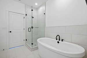 Full bathroom with tile walls, a stall shower, and a soaking tub