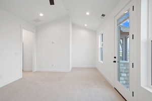 Empty room featuring light colored carpet, recessed lighting, vaulted ceiling, and baseboards