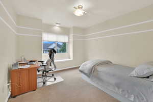 Bedroom featuring light colored carpet, an office area, and baseboards