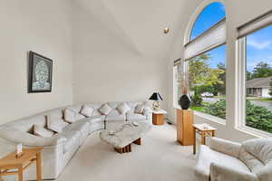 Living room featuring plenty of natural light, light colored carpet, and high vaulted ceiling