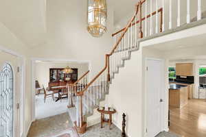 Foyer featuring a chandelier, a high ceiling, stairs, and baseboards