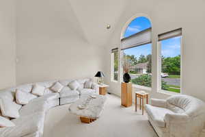 Living room featuring high vaulted ceiling and light colored carpet
