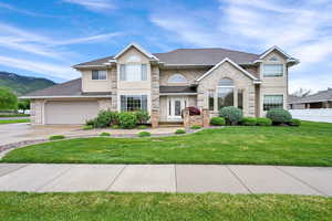 View of front of property featuring driveway, a garage, stucco siding, roof with shingles, and a mountain view