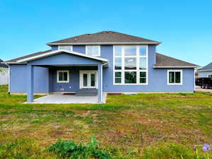 Back of house with a patio, stucco siding, a lawn, and roof with shingles