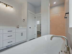 Full bathroom featuring a soaking tub, vanity, and recessed lighting